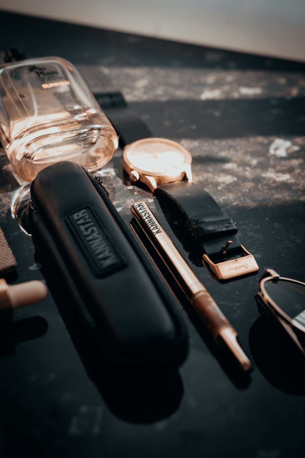 A collection of men's accessories on a dark surface