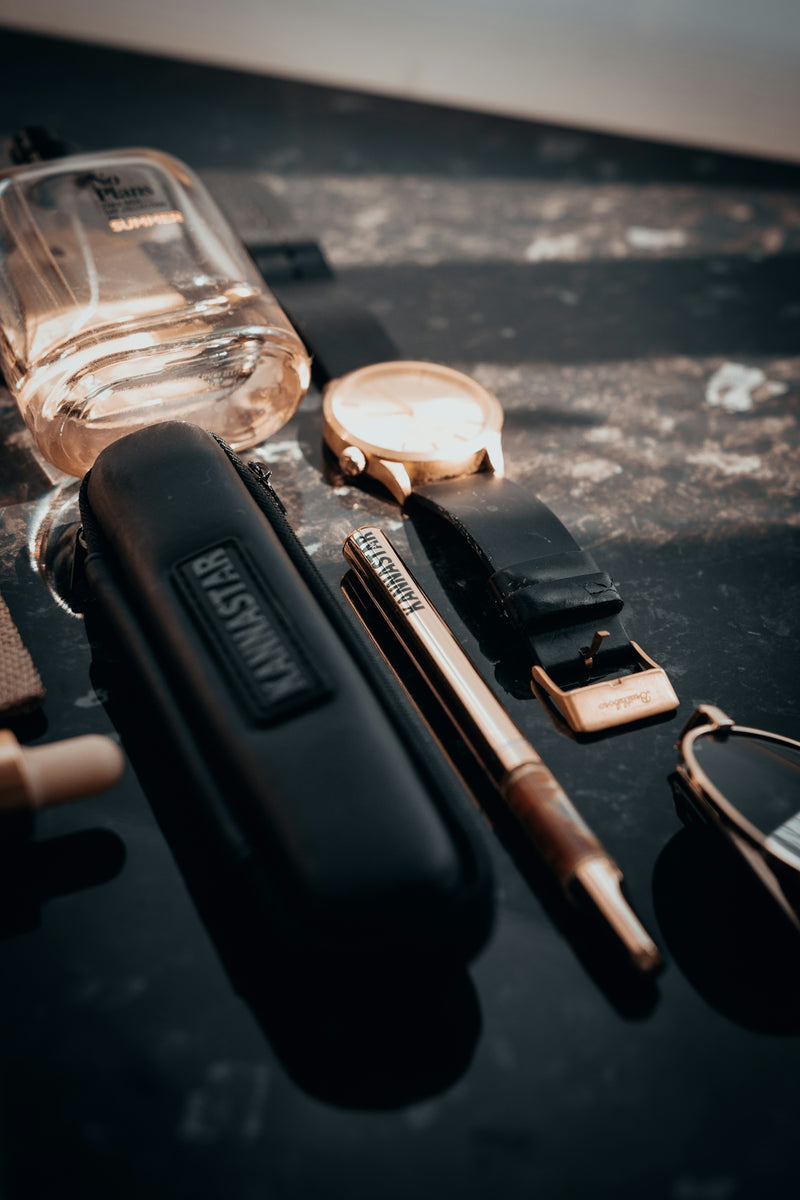 A collection of men's accessories on a dark surface